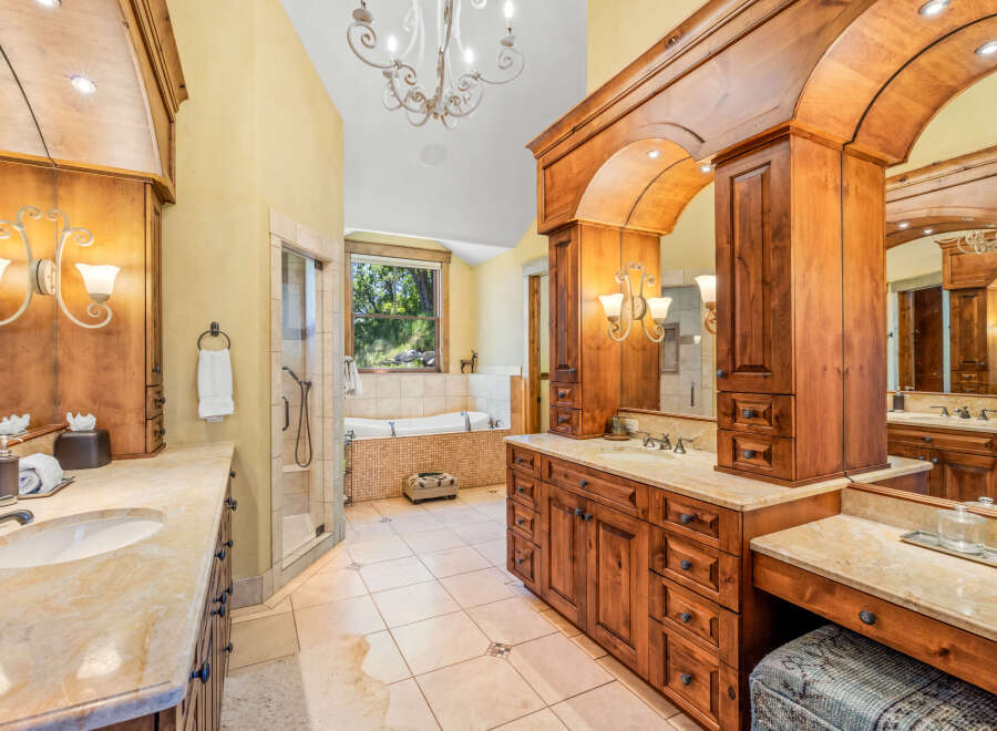 Indulge in luxury in this stunning bathroom featuring a spacious walk-in shower and a deep soaking tub with a scenic window view.