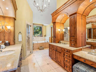 Indulge in luxury in this stunning bathroom featuring a spacious walk-in shower and a deep soaking tub with a scenic window view.