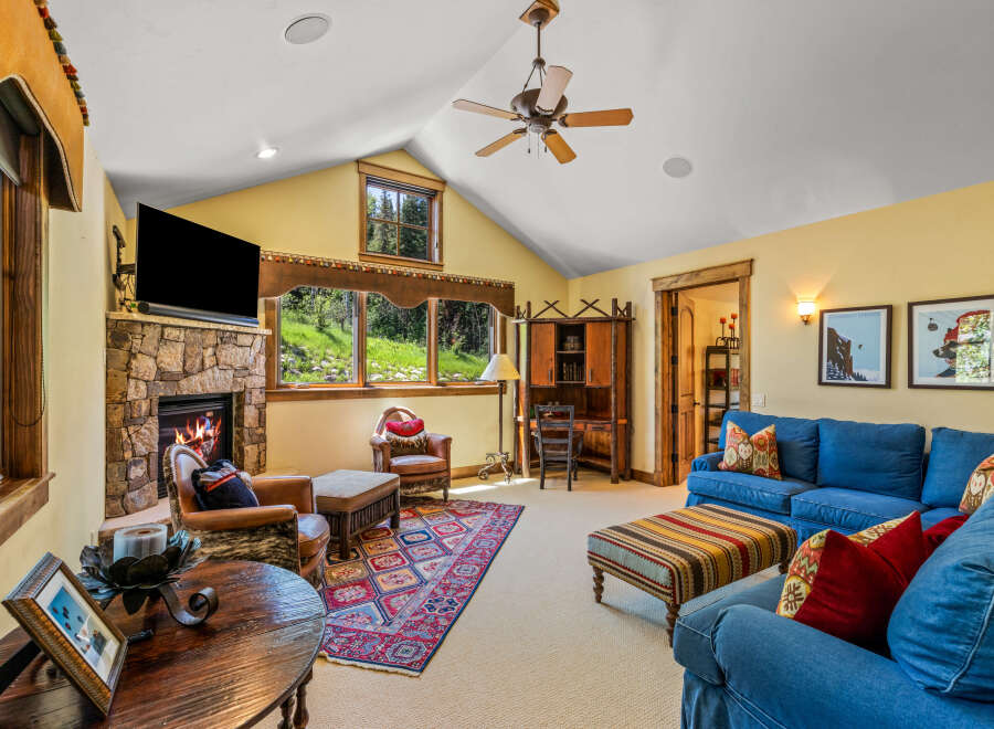 Cozy living room featuring a stone fireplace and large windows with scenic views.