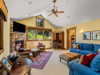 Cozy living room featuring a stone fireplace and large windows with scenic views.