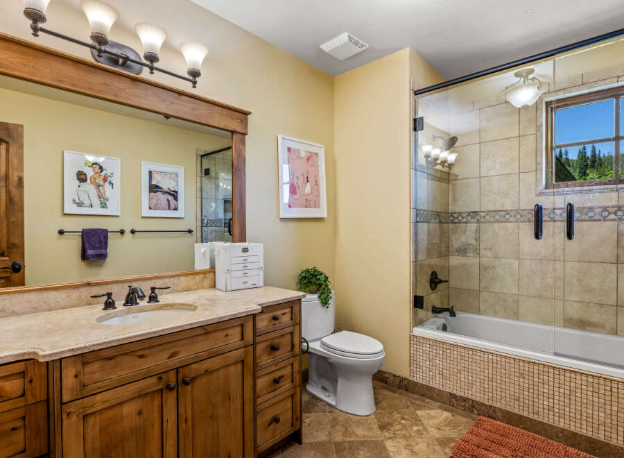 This charming bathroom features a spacious wooden vanity with a granite countertop and a large mirror, perfect for your morning routine.