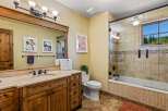 This charming bathroom features a spacious wooden vanity with a granite countertop and a large mirror, perfect for your morning routine.