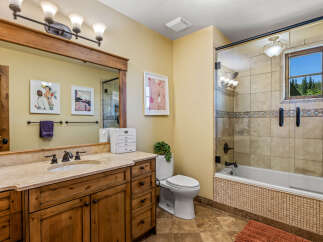 This charming bathroom features a spacious wooden vanity with a granite countertop and a large mirror, perfect for your morning routine.