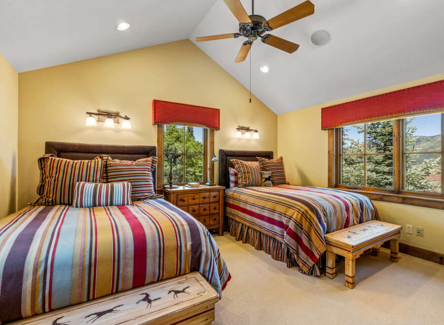 This charming bedroom features two comfortable beds adorned with vibrant, striped bedding and decorative pillows.