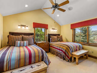 This charming bedroom features two comfortable beds adorned with vibrant, striped bedding and decorative pillows.