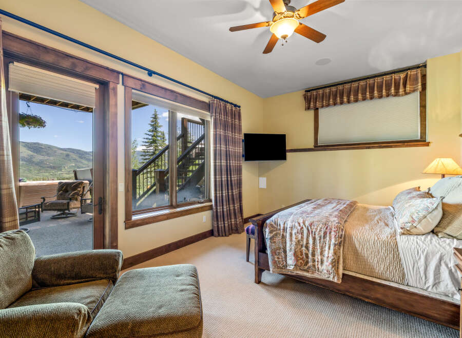 Experience breathtaking mountain views from this charming bedroom, complete with a cozy seating area and direct access to an outdoor patio.