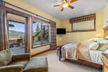 Experience breathtaking mountain views from this charming bedroom, complete with a cozy seating area and direct access to an outdoor patio.