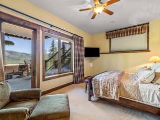 Experience breathtaking mountain views from this charming bedroom, complete with a cozy seating area and direct access to an outdoor patio.