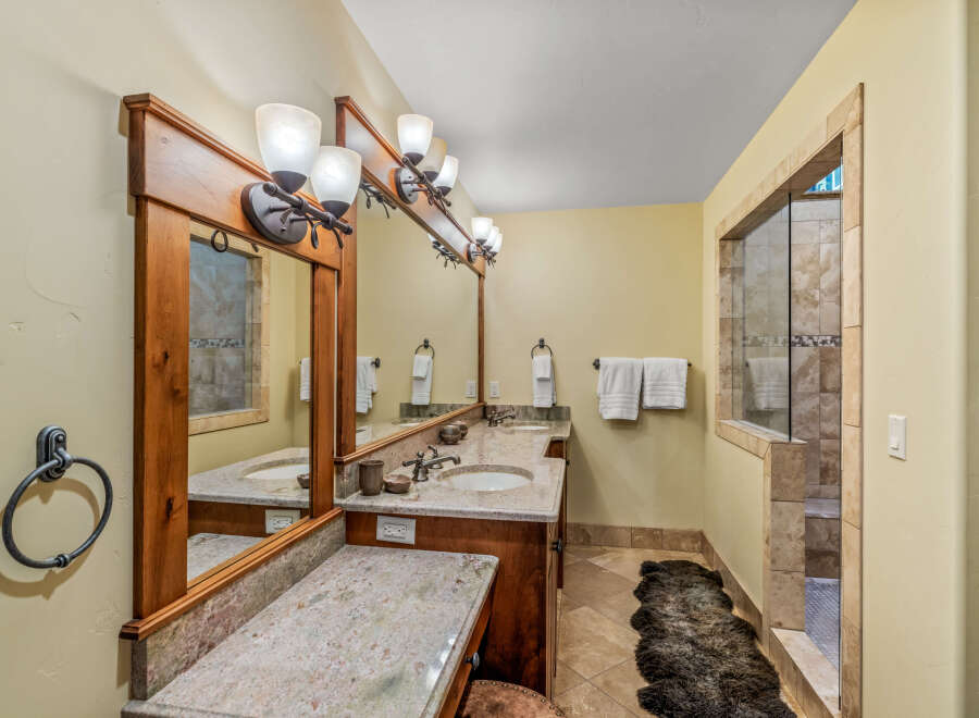 This luxurious bathroom features a spacious double vanity with granite countertops and elegant wooden cabinetry.