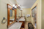 This luxurious bathroom features a spacious double vanity with granite countertops and elegant wooden cabinetry.