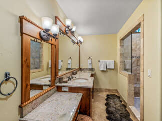 This luxurious bathroom features a spacious double vanity with granite countertops and elegant wooden cabinetry.