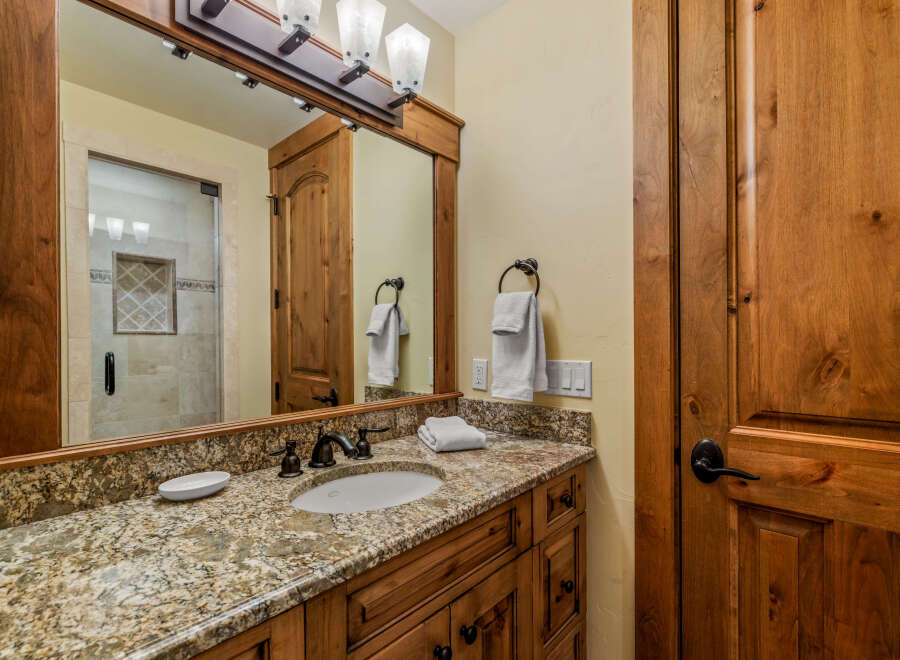 This bathroom showcases a beautiful granite countertop with an undermount sink and oil-rubbed bronze fixtures.