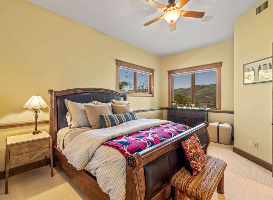 Experience luxury mountain living in this exquisite bedroom, featuring a grand wooden sleigh bed adorned with plush pillows and a vibrant, patterned throw.