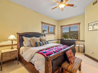 Experience luxury mountain living in this exquisite bedroom, featuring a grand wooden sleigh bed adorned with plush pillows and a vibrant, patterned throw.