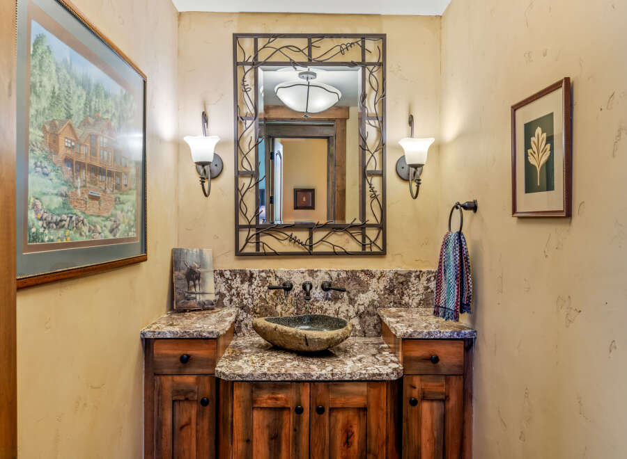 This rustic powder room features a unique stone vessel sink atop a granite countertop and a custom wood vanity.