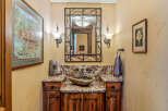 This rustic powder room features a unique stone vessel sink atop a granite countertop and a custom wood vanity.