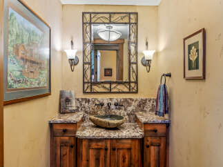This rustic powder room features a unique stone vessel sink atop a granite countertop and a custom wood vanity.