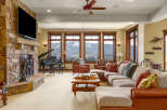 Experience luxury mountain living in this stunning great room, featuring a grand piano and a massive stone fireplace.