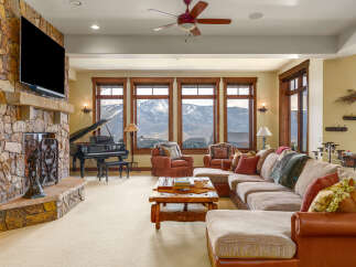 Experience luxury mountain living in this stunning great room, featuring a grand piano and a massive stone fireplace.