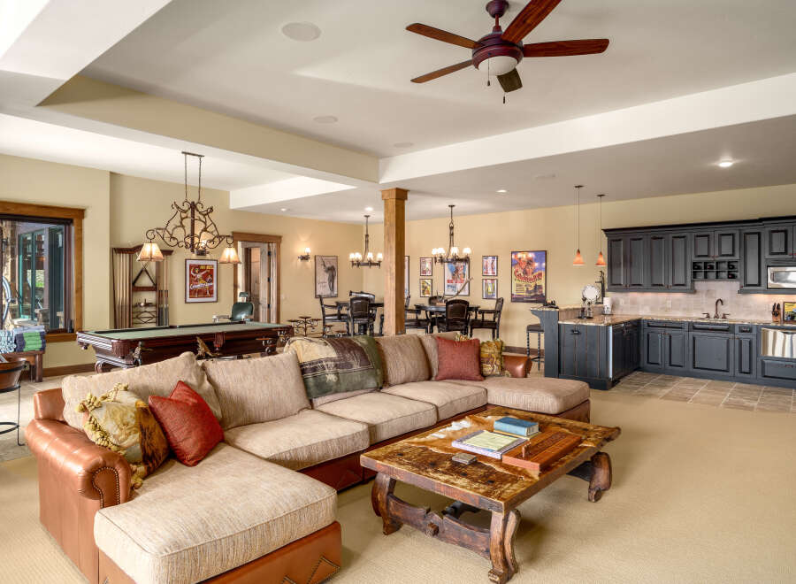 This spacious basement living area offers a perfect blend of entertainment and relaxation, featuring a full-size pool table and a cozy sectional sofa.