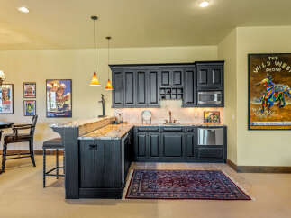 Step into a Western-themed entertainment space featuring a stylish bar with granite countertops and dark wood cabinetry.