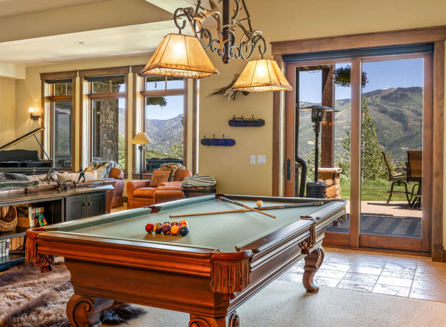 Experience luxury mountain living in this stunning home featuring a spacious game room with a billiards table, perfect for entertaining.