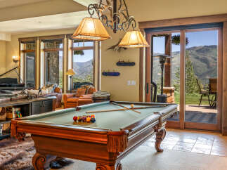 Experience luxury mountain living in this stunning home featuring a spacious game room with a billiards table, perfect for entertaining.