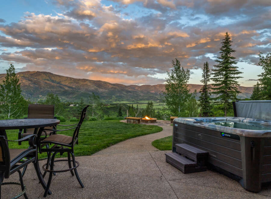 Experience luxury outdoor living with this stunning property featuring a relaxing hot tub and a cozy fire pit, perfect for enjoying breathtaking mountain views.