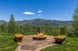Enjoy breathtaking mountain views from this stunning outdoor living space, complete with a cozy fire pit and stone seating.