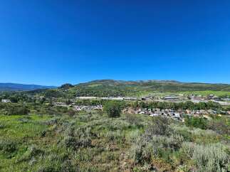 Discover breathtaking panoramic views from this elevated vantage point, overlooking a charming town nestled amidst rolling green hills and distant mountains.