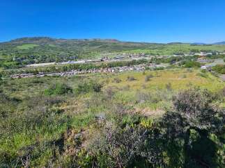 Discover breathtaking panoramic views from this elevated vantage point, overlooking a charming town nestled amidst rolling green hills and distant mountains.