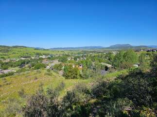 Discover this charming property nestled amidst rolling green hills and a vibrant blue sky.