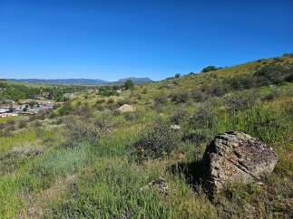 Discover breathtaking panoramic views from this elevated vantage point, overlooking a charming town nestled amidst rolling green hills and distant mountains.