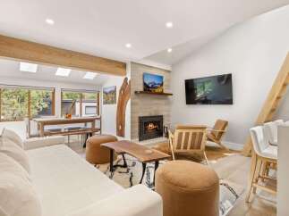 Experience modern mountain living in this beautifully designed living space, featuring a cozy fireplace and a large TV for entertainment.