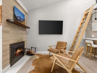 Experience cozy living with a modern fireplace and a stunning mountain landscape artwork.