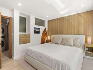 Experience modern comfort in this serene bedroom, featuring a plush king-sized bed and a striking wood-slat accent wall.