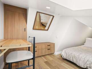 Discover this charming attic room, featuring a cozy single bed with a nature-inspired duvet and a minimalist wooden dresser.