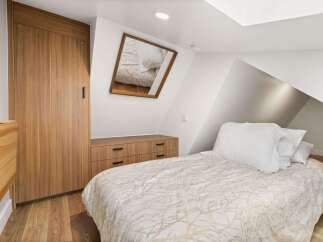 This cozy bedroom features a stylish wooden wardrobe and a matching dresser, offering ample storage.