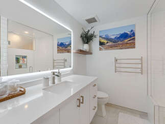 Experience modern luxury in this stunning bathroom featuring a sleek vanity with a white quartz countertop and integrated sink.