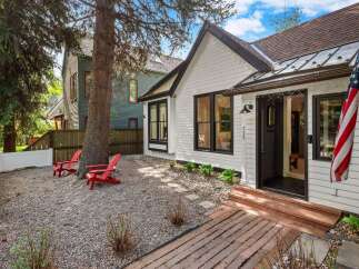 Charming white cottage with black trim and a welcoming front porch featuring an American flag.