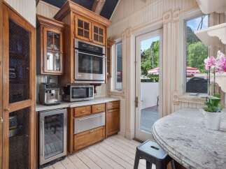 This charming kitchen features custom wood cabinetry, a built-in oven and microwave, and a convenient coffee station.