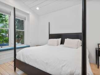 Experience ultimate comfort in this beautifully appointed bedroom, featuring a luxurious four-poster bed dressed in crisp white linens.