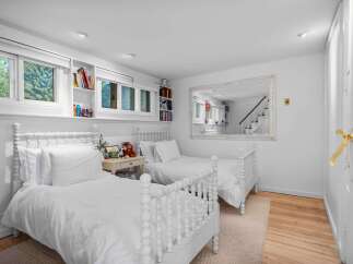 This charming bedroom features two white spindle beds, perfect for siblings or guests.