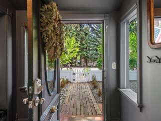 Step into this charming entryway featuring a decorative wreath and a view of a brick pathway leading to a white picket gate.