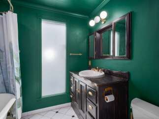 Step into this charming bathroom featuring a vibrant emerald green accent wall, creating a bold and luxurious atmosphere.