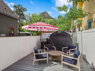 Enjoy outdoor living in this charming patio space, complete with comfortable seating and a round wooden table perfect for al fresco dining.