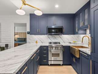 Experience luxury in this stunning kitchen featuring deep navy cabinetry with elegant brass hardware.
