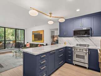 Experience modern living in this stunning kitchen featuring deep navy cabinetry and sleek marble countertops.