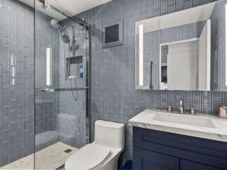 Experience modern luxury in this stunning bathroom, featuring a sleek glass-enclosed shower with a rainfall showerhead and elegant gray subway tile.