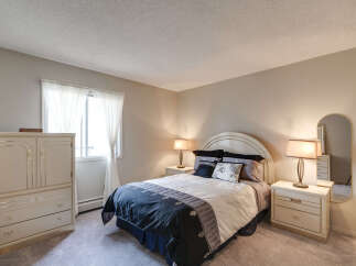 Discover comfort and style in this inviting bedroom, featuring a plush queen-size bed with elegant bedding and decorative pillows.